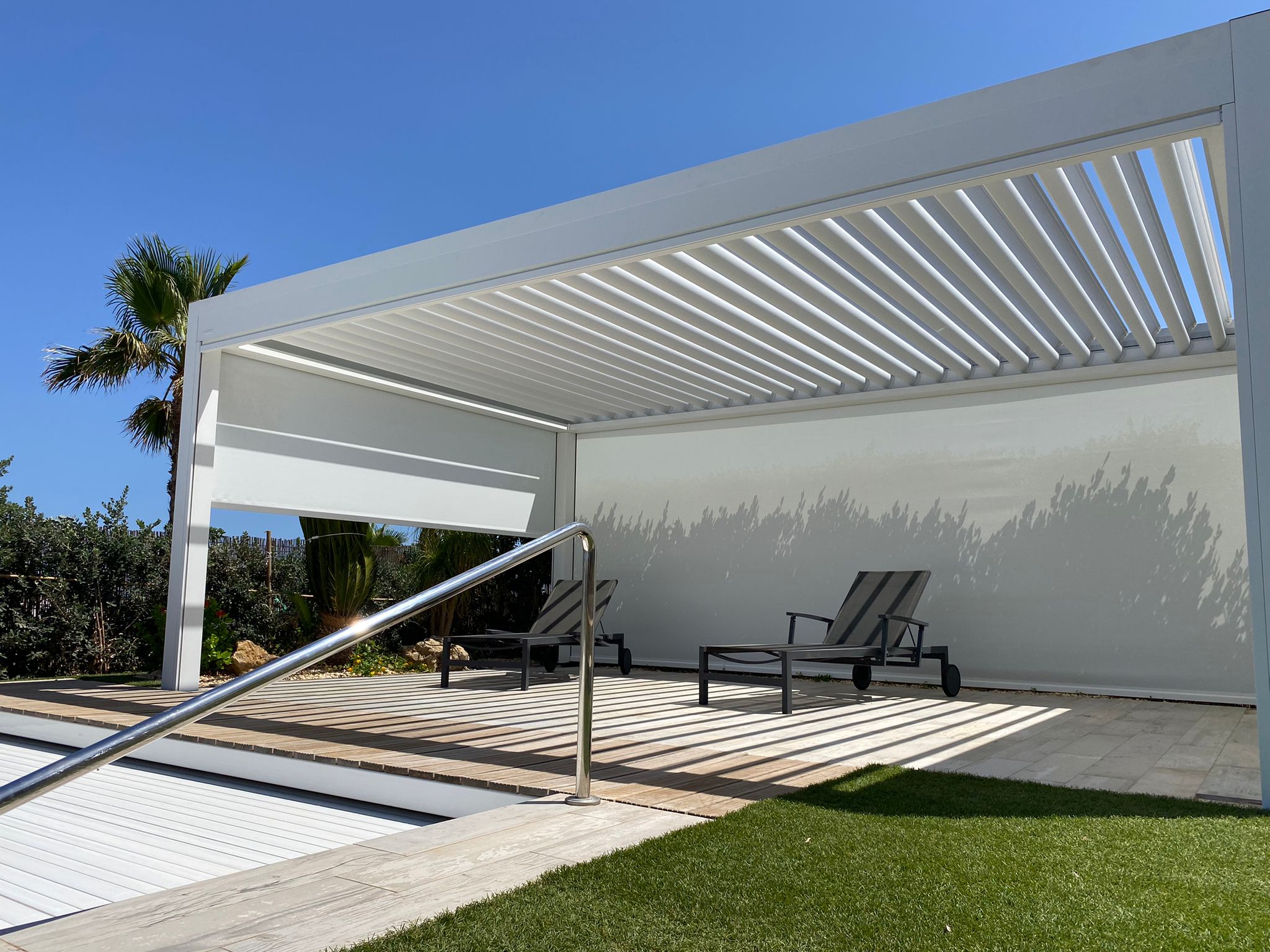 Pérgola bioclimática con palmeras y cielo despejado